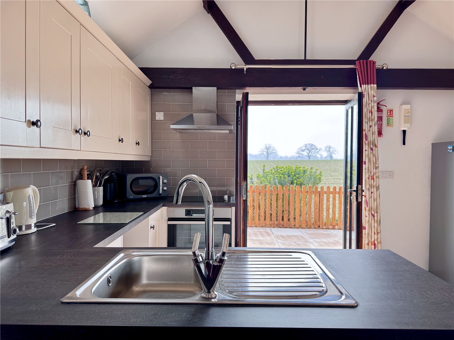 Well equipped kitchen opening onto enclosed patio with countryside view at holiday accommodation in Norfolk